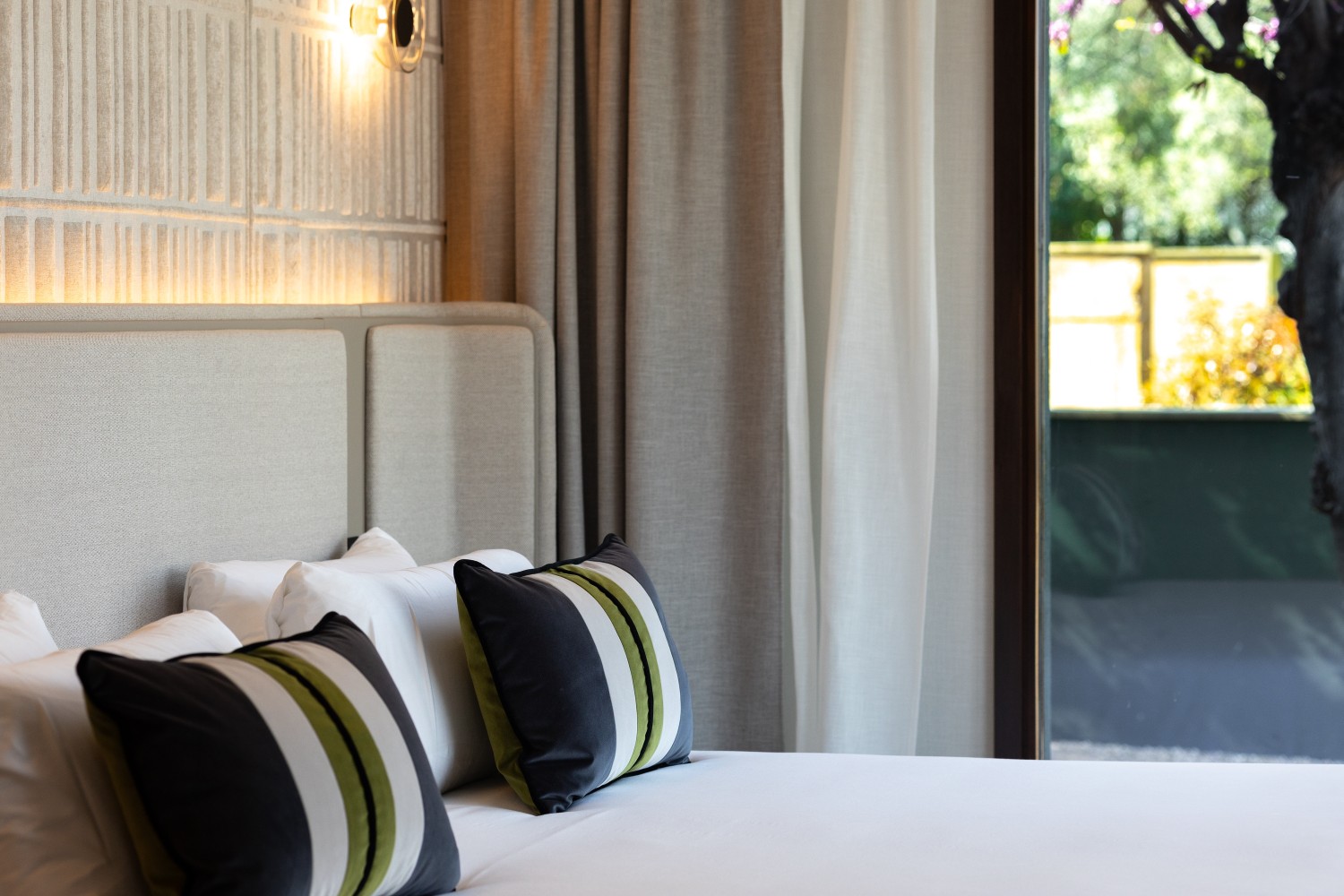 Close-up of the designer headboard and pillow arrangement, highlighting the noble fabrics and the high standard of rest.